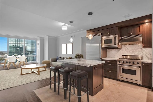 kitchen featuring tasteful backsplash, built in appliances, light hardwood / wood-style floors, decorative light fixtures, and a kitchen island