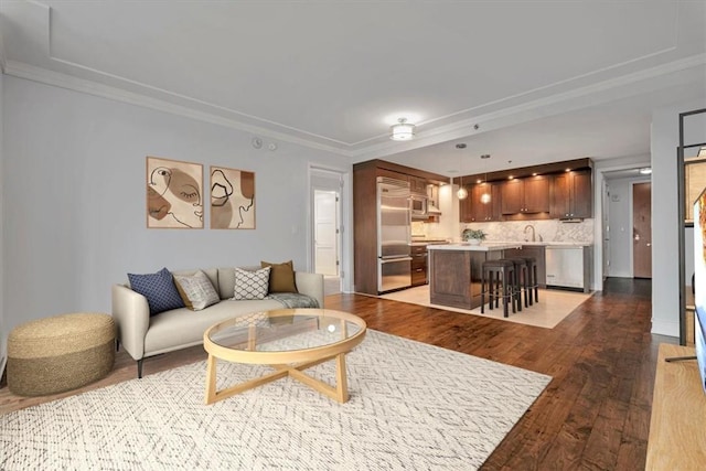 living room featuring dark hardwood / wood-style flooring, ornamental molding, and sink