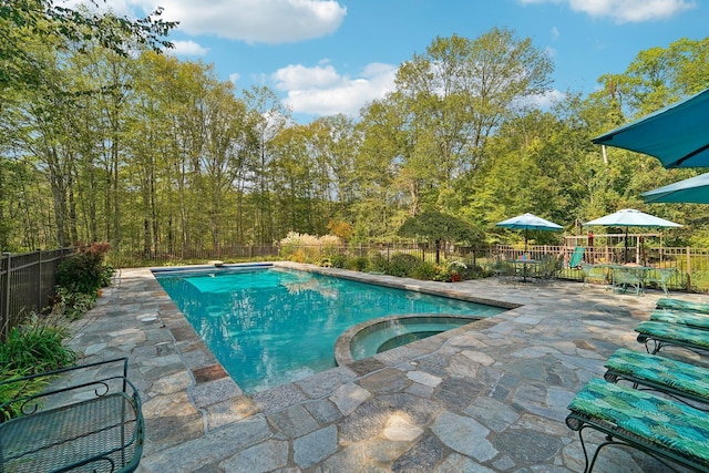 view of pool with a pool with connected hot tub, fence, and a patio