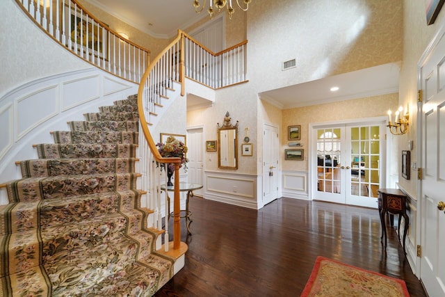 interior space with ornamental molding, french doors, wainscoting, and a decorative wall