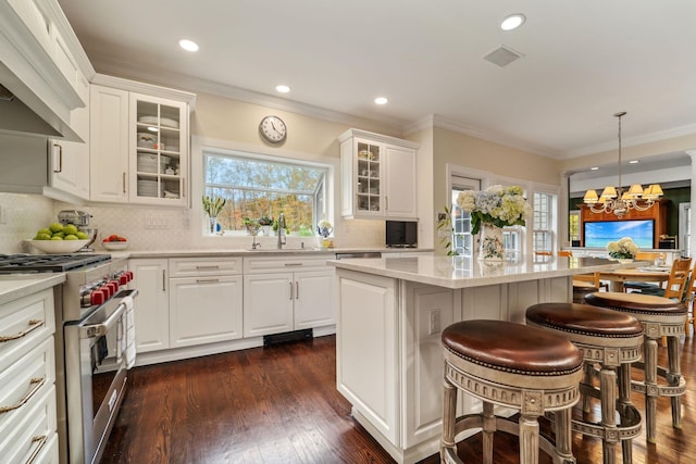 kitchen with dark wood-type flooring, stainless steel range, wall chimney range hood, and a sink