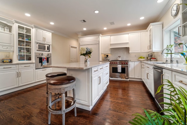 kitchen with appliances with stainless steel finishes, a kitchen island, a sink, and white cabinetry