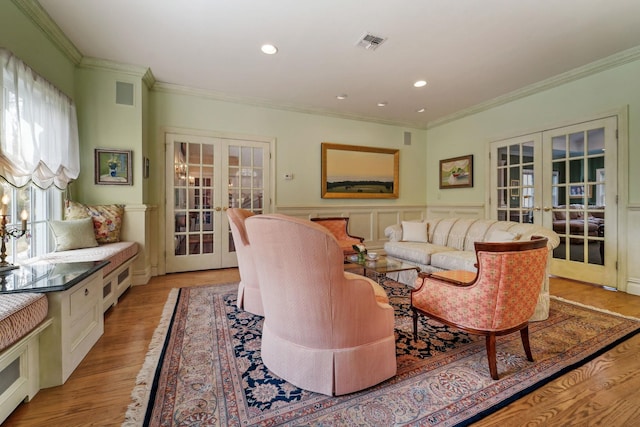 living area featuring ornamental molding, french doors, visible vents, and light wood finished floors