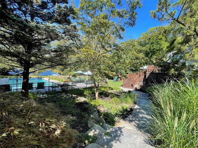 view of yard with fence, a pool, and a playground