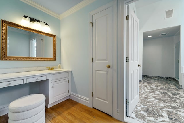 bathroom with baseboards, visible vents, wood finished floors, crown molding, and vanity