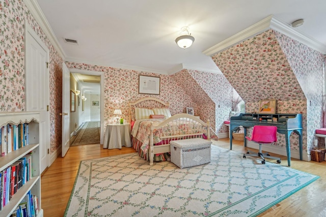 bedroom with wood finished floors, visible vents, crown molding, and wallpapered walls