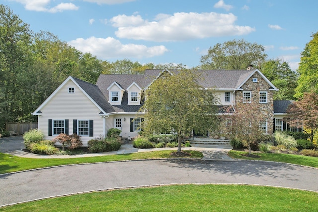 view of front of property with a front yard, stone siding, and fence