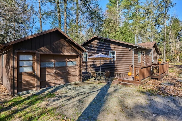 view of front facade featuring a garage, an outbuilding, and a wooden deck