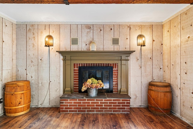 room details with wood walls, wood-type flooring, crown molding, and a brick fireplace