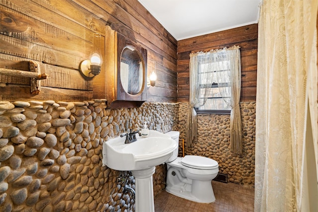 bathroom featuring wooden walls and toilet