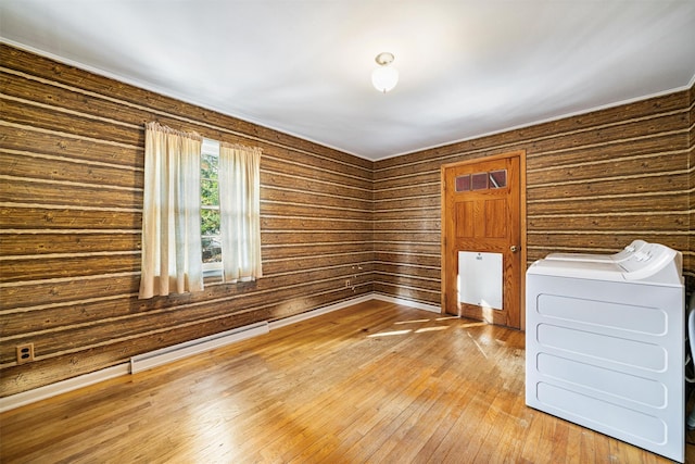 interior space with hardwood / wood-style floors, wood walls, baseboard heating, and washing machine and clothes dryer