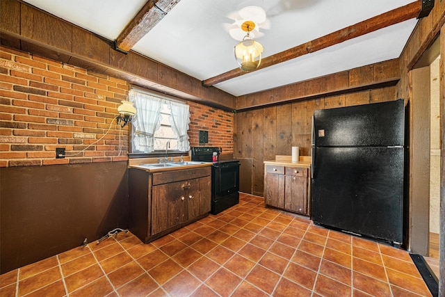 kitchen featuring beam ceiling, sink, tile patterned floors, wooden walls, and black appliances