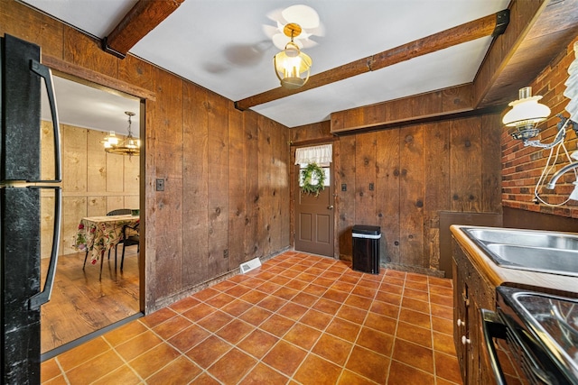 kitchen with black fridge, sink, beam ceiling, range with electric stovetop, and wood walls