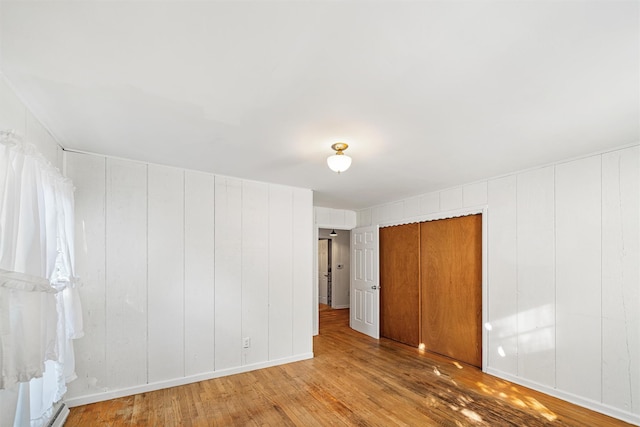 unfurnished room featuring wooden walls, hardwood / wood-style floors, and a baseboard radiator