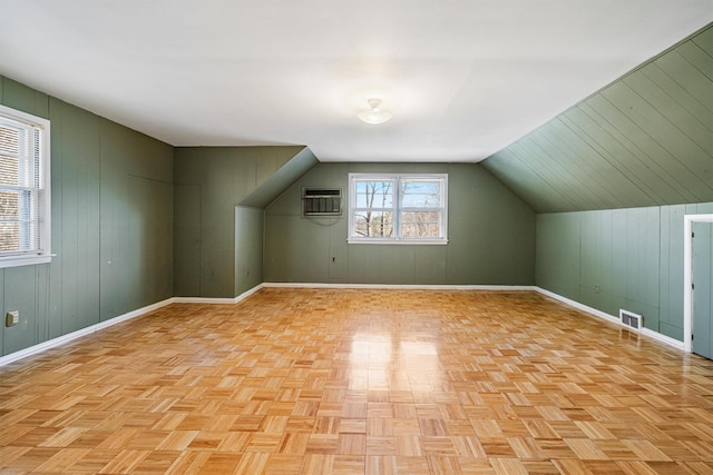 additional living space with lofted ceiling, wooden walls, and light parquet flooring