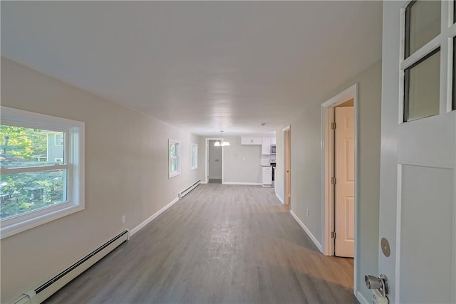 corridor with a chandelier, light hardwood / wood-style flooring, and baseboard heating