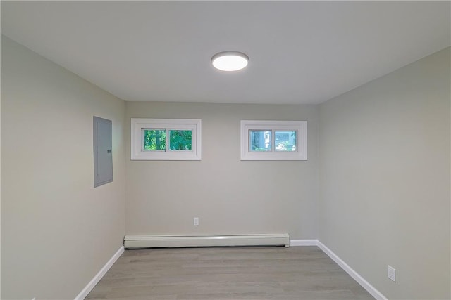 spare room with electric panel, light hardwood / wood-style flooring, and a baseboard heating unit