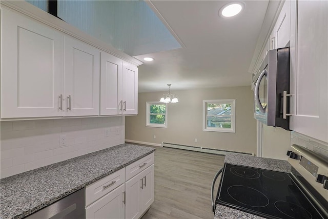 kitchen featuring white cabinets, range, light hardwood / wood-style floors, and an inviting chandelier