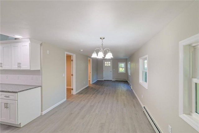 interior space featuring light wood-type flooring, a baseboard radiator, and an inviting chandelier