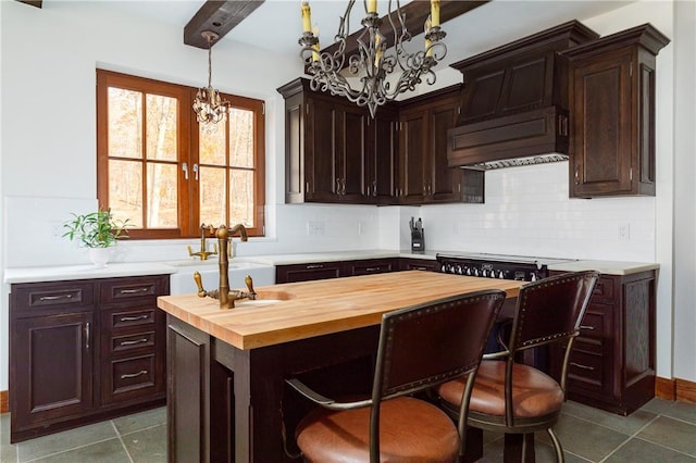 kitchen with sink, butcher block counters, backsplash, a notable chandelier, and custom exhaust hood