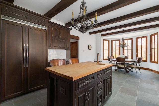 kitchen with wood counters, a center island, hanging light fixtures, a notable chandelier, and backsplash