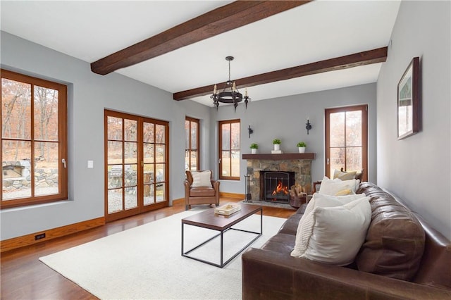 living room featuring hardwood / wood-style floors, beam ceiling, a fireplace, and a notable chandelier