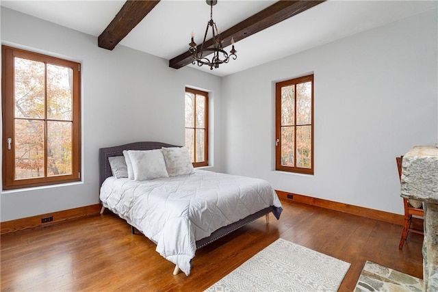 bedroom with dark hardwood / wood-style floors, a chandelier, and beam ceiling