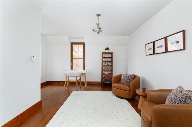 sitting room featuring dark wood-type flooring and an inviting chandelier