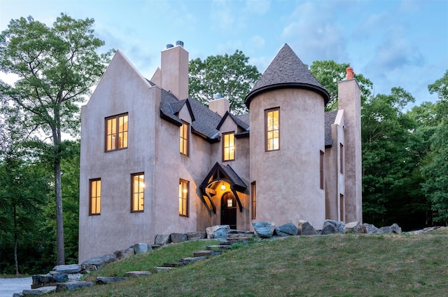 view of front of property with stucco siding, a front lawn, and a chimney