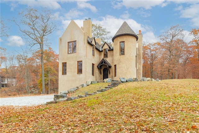 view of front facade featuring stucco siding, a front lawn, and a chimney