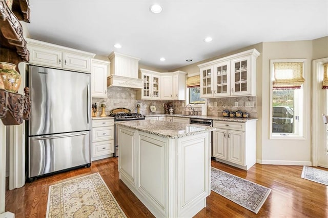 kitchen with decorative backsplash, a wealth of natural light, a kitchen island, and stainless steel appliances