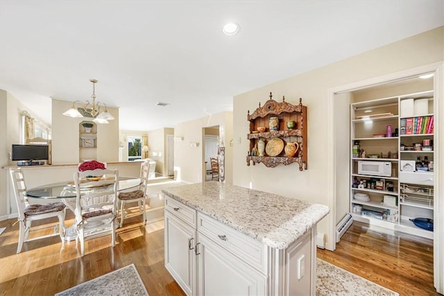 kitchen with pendant lighting, a center island, dark hardwood / wood-style floors, white cabinetry, and a chandelier