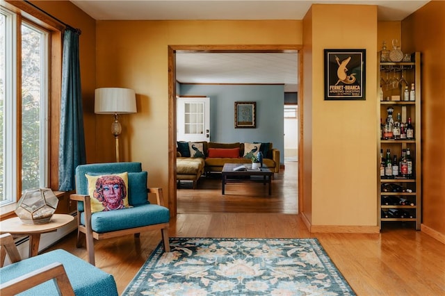 sitting room featuring bar and light hardwood / wood-style floors