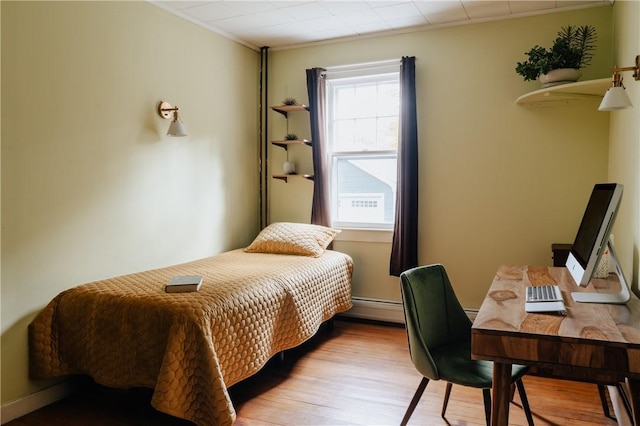 bedroom featuring multiple windows, crown molding, a baseboard radiator, and light wood-type flooring