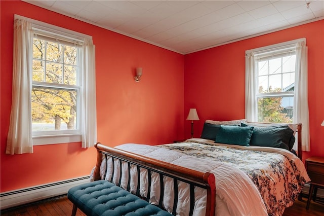 bedroom featuring multiple windows, hardwood / wood-style floors, and a baseboard radiator