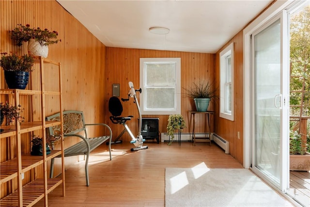 living area with light hardwood / wood-style floors, wooden walls, and a baseboard heating unit