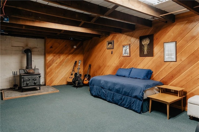 carpeted bedroom with beam ceiling, a wood stove, and wooden walls