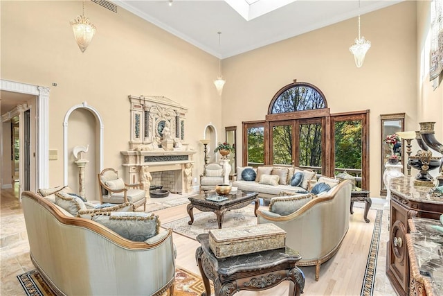 living room featuring a fireplace, light wood-type flooring, a towering ceiling, and crown molding