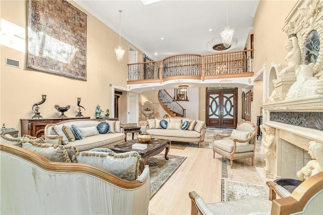 living room with a premium fireplace, a towering ceiling, and light hardwood / wood-style floors