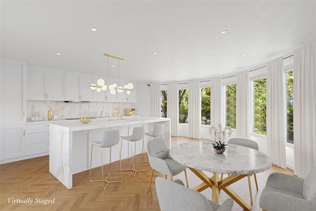 kitchen featuring decorative backsplash, white cabinetry, light parquet flooring, and hanging light fixtures