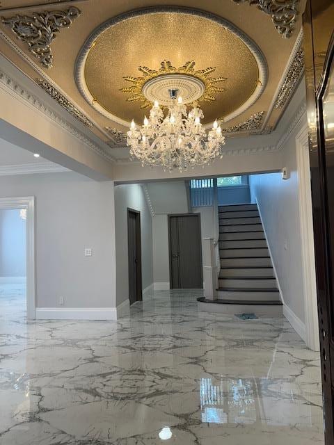 interior space with a notable chandelier, ornamental molding, and a tray ceiling