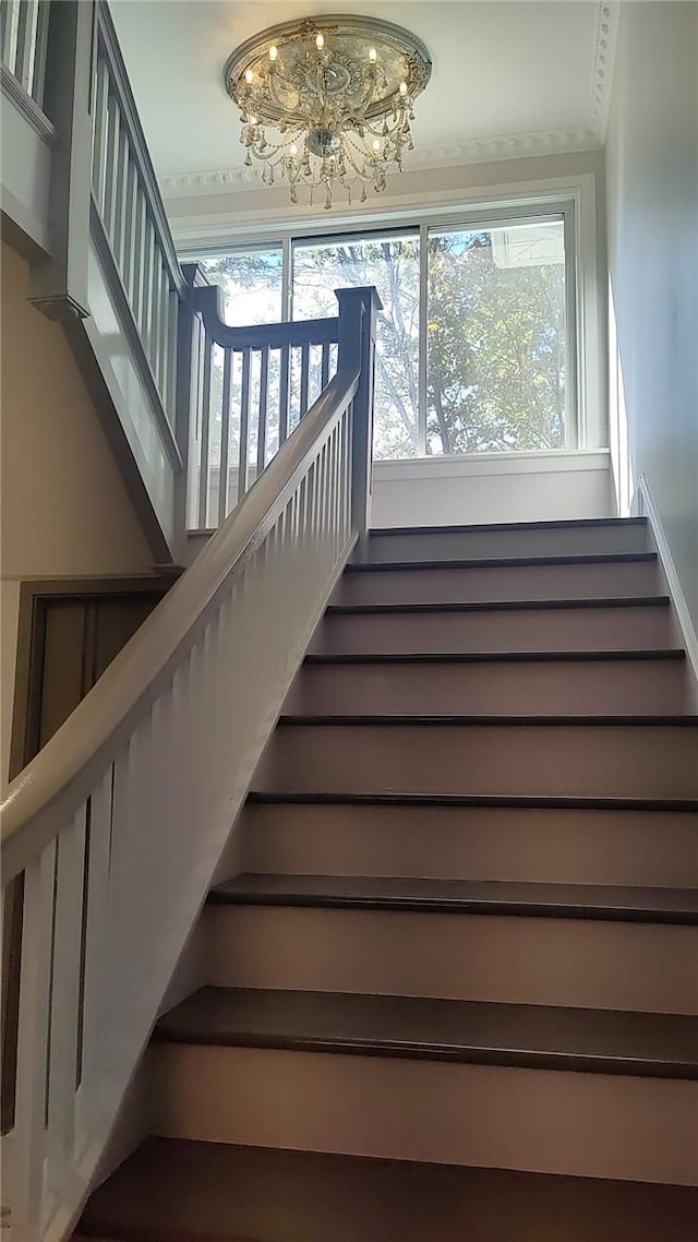 stairway featuring a notable chandelier