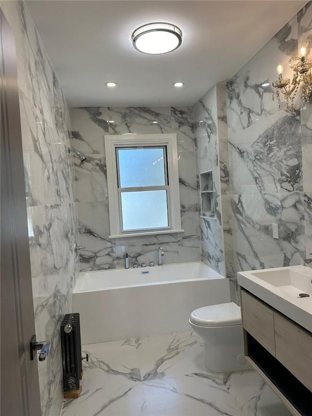 bathroom featuring a tub to relax in, vanity, tile walls, and toilet