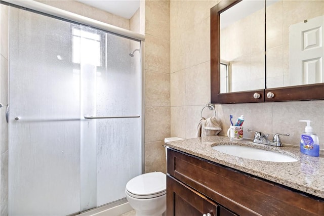 bathroom with backsplash, an enclosed shower, toilet, vanity, and tile walls