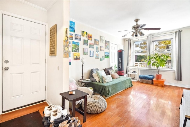 sitting room with light wood-type flooring, ceiling fan, and crown molding