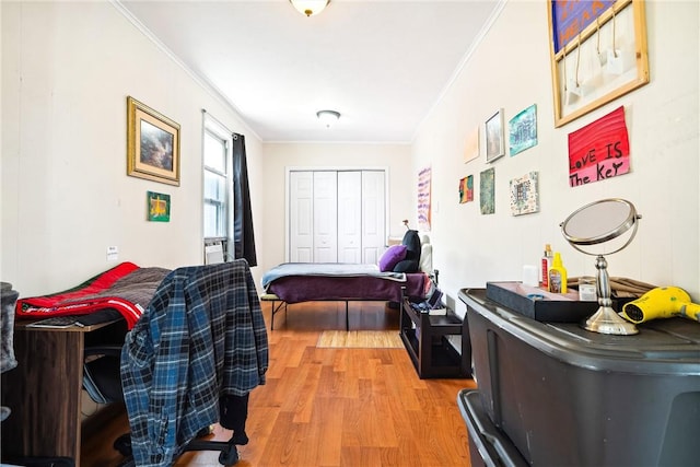 bedroom with light hardwood / wood-style flooring, a closet, and crown molding