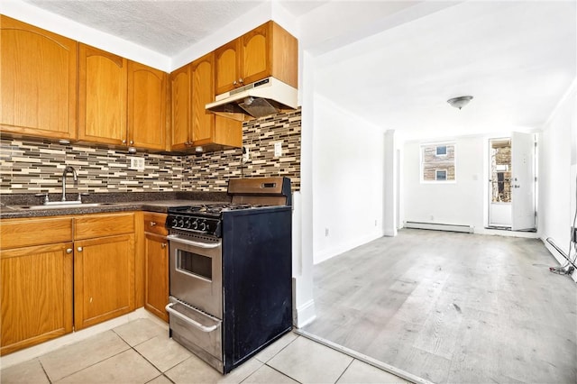 kitchen featuring stainless steel range, sink, baseboard heating, decorative backsplash, and light wood-type flooring