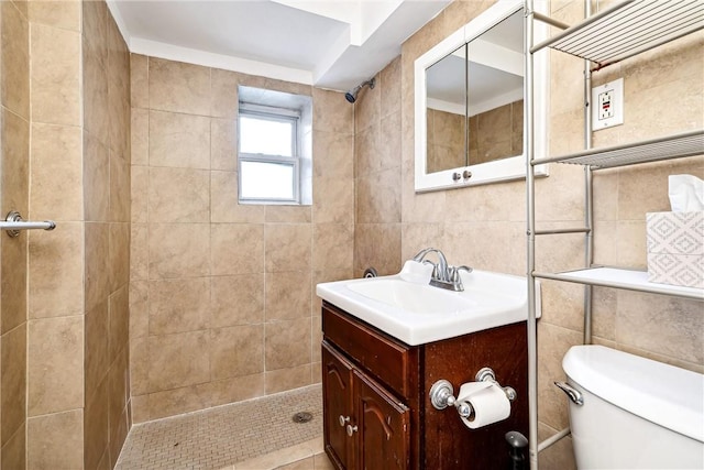 bathroom featuring tile patterned floors, vanity, tiled shower, tile walls, and toilet