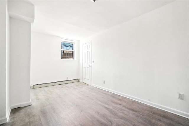 empty room featuring hardwood / wood-style flooring and a baseboard heating unit