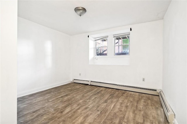 unfurnished room featuring wood-type flooring and a baseboard heating unit